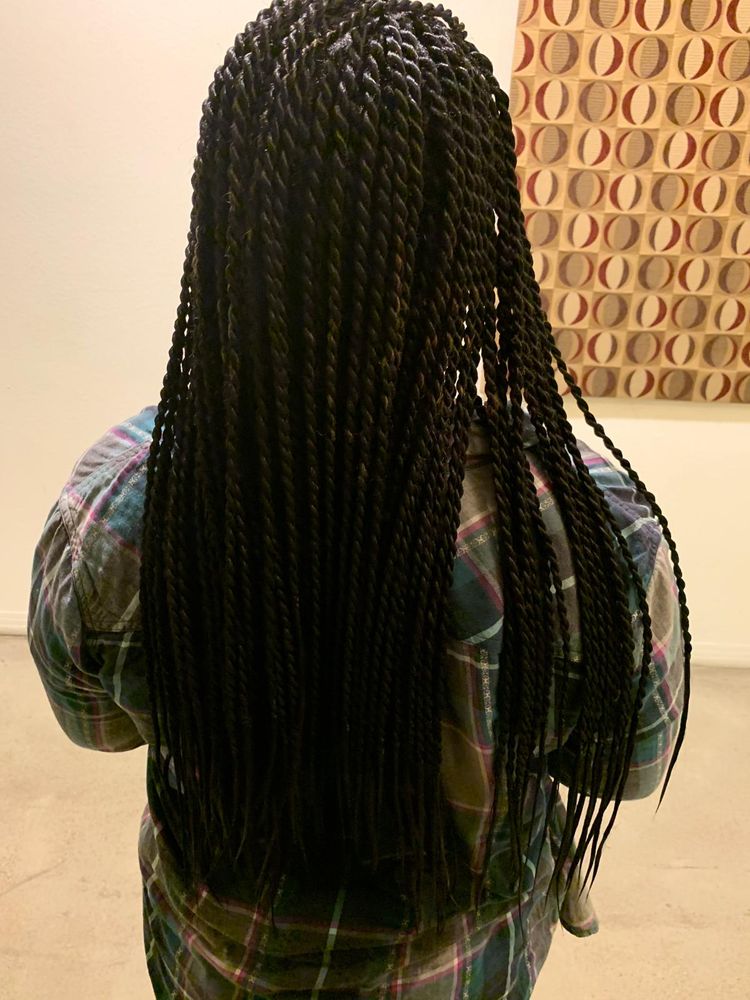 A woman with long braids standing in front of a painting